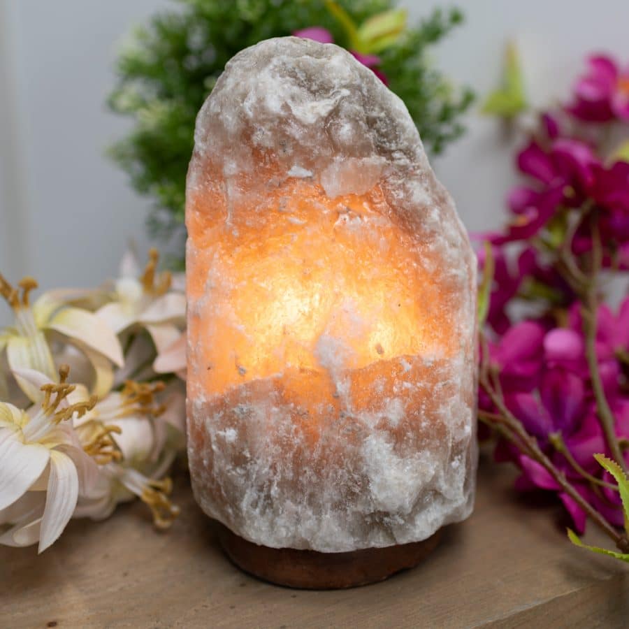 Himalaya Salzkristalllampe leuchtend auf Tisch mit Blumen
