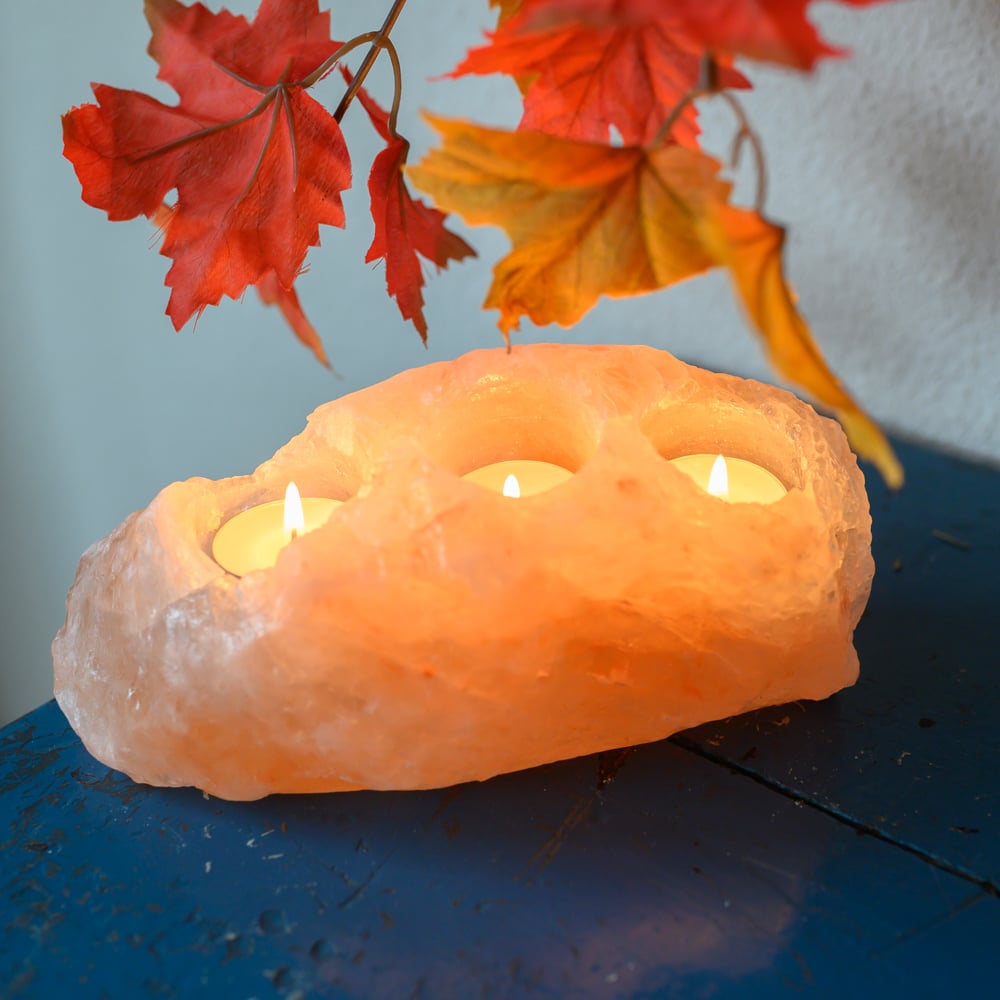 Himalaya Salzlampe Salzlampenteelichthalter mit brennenden Teelichtern auf Tisch mit herbstlichen Blättern