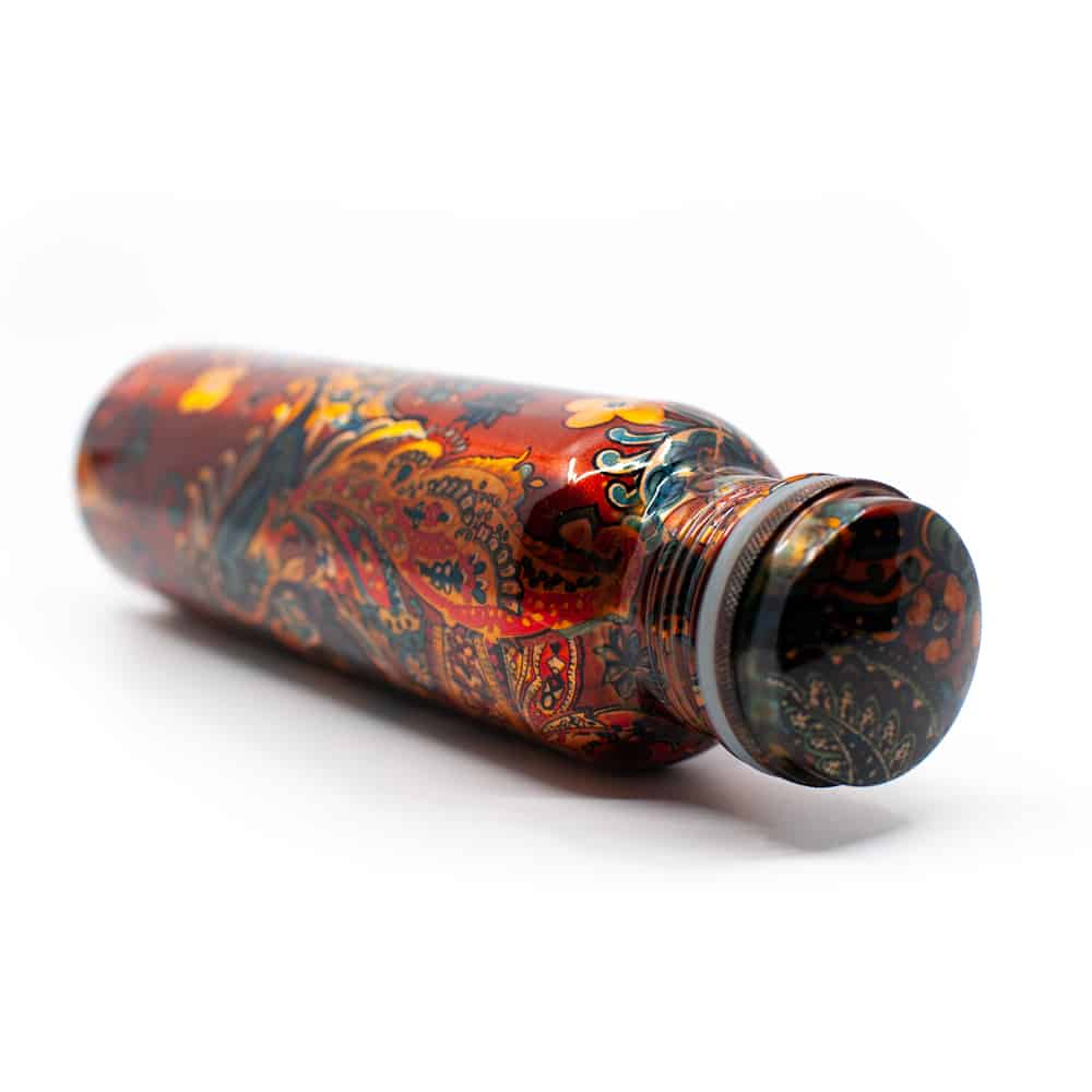 schöne Kupferflasche mit floralem Design liegend auf weißem Hintergrund