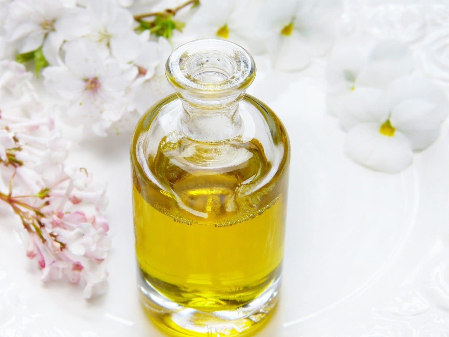 gelbliches Duftöl in Flasche mit weißen Blumen