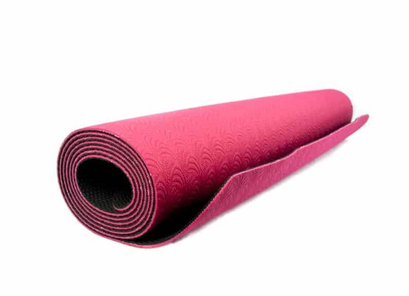 Pinke aufgerollte Yogamatte auf weißem Hintergrund