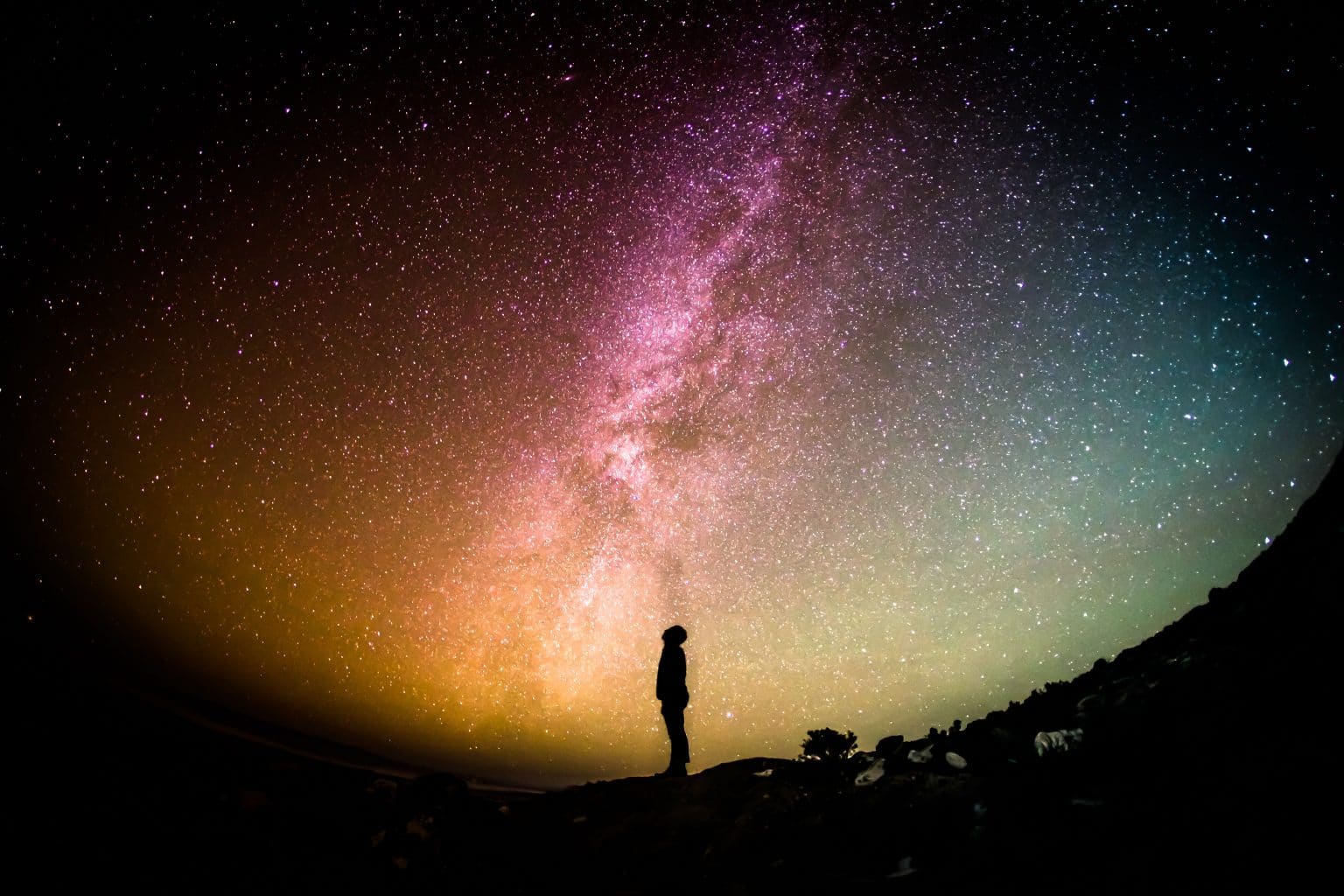 silhouette schaut zu buntem Sternenhimmel