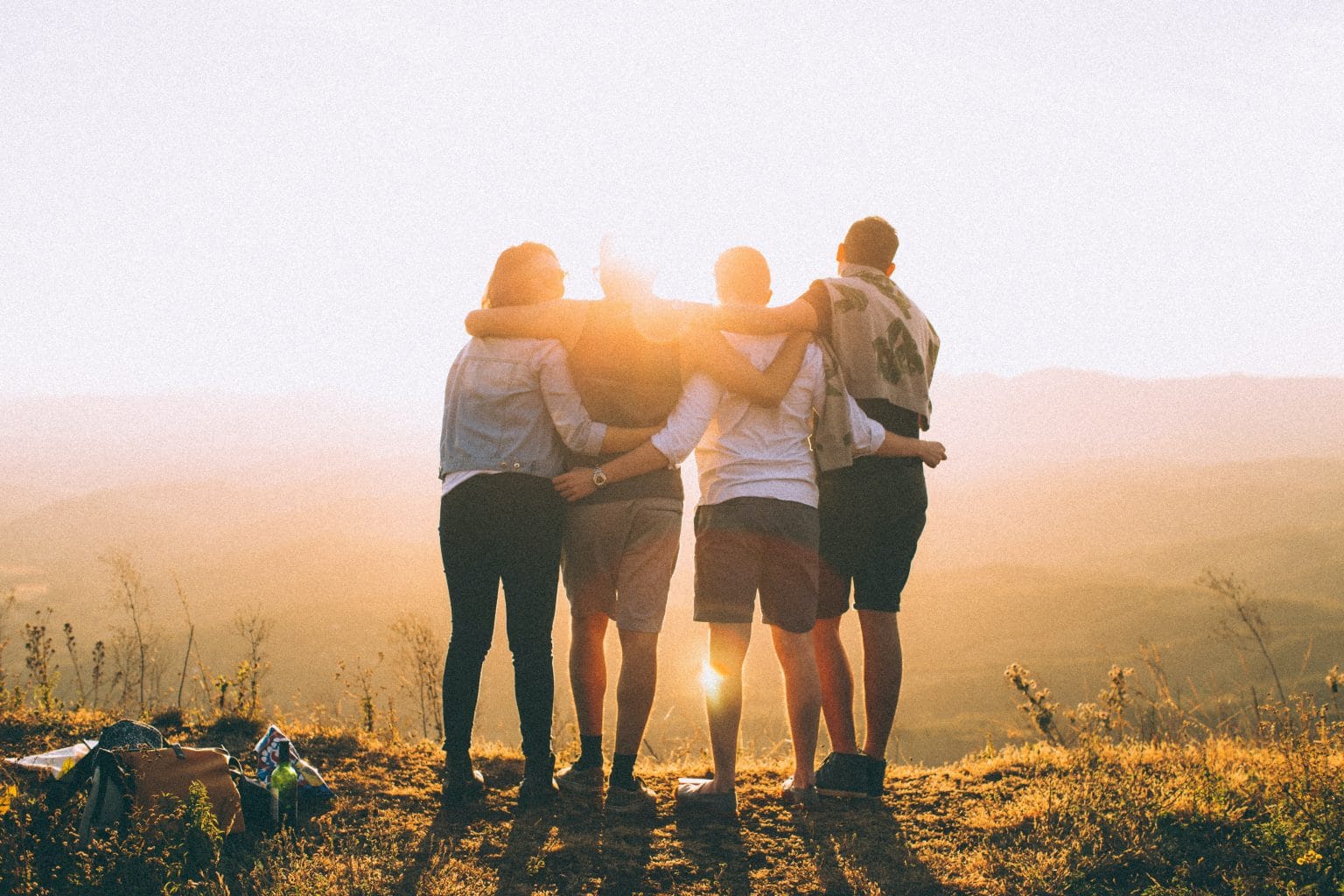 Sternzeichen Waage vier Freunde umarmen sich in Natur vor Sonnenuntergang
