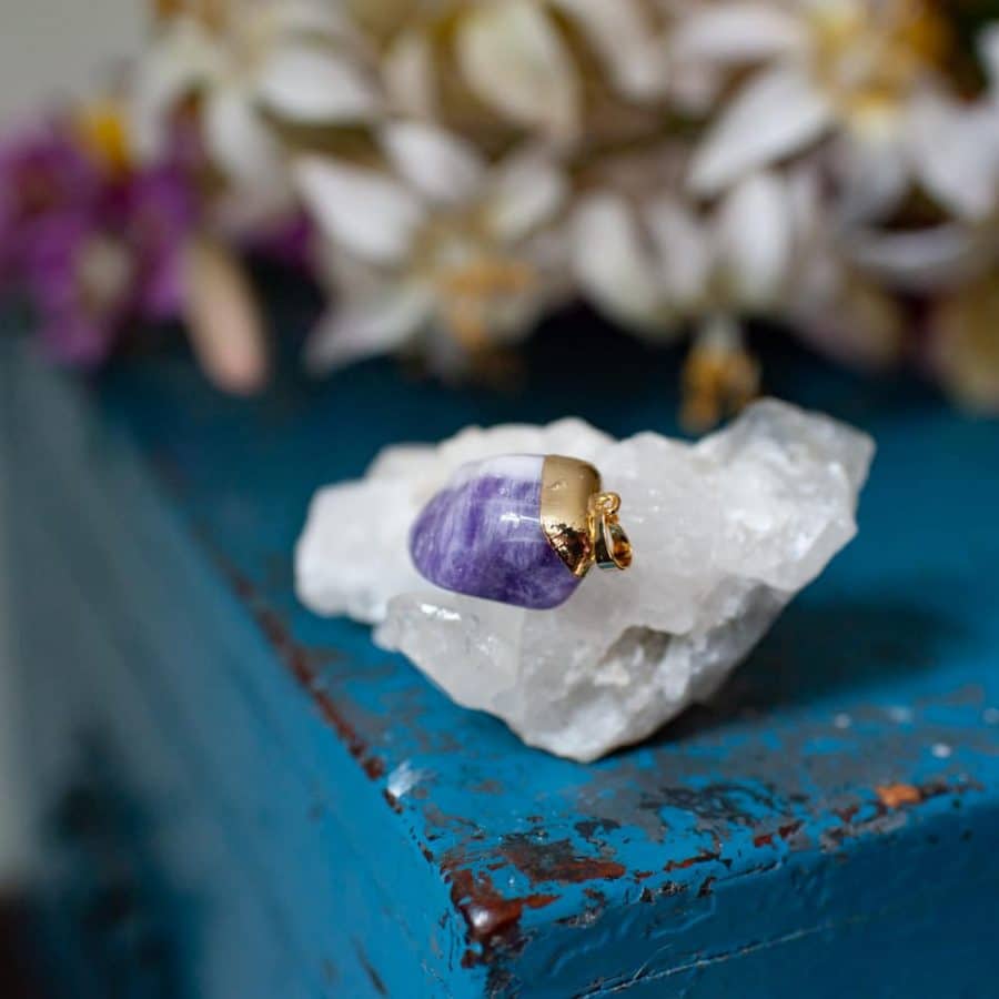 Amethyst Anhänger für Sternzeichen Wassermann auf Kristall auf Blauem Holz mit Blumen
