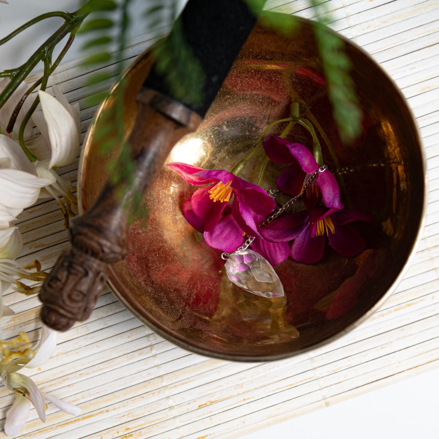 Klangschale mit Anstereicher und Blumen und Pendel