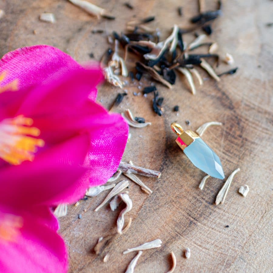 Halschakra Edelstein Anhänger Amazonit auf Holz mit Blume