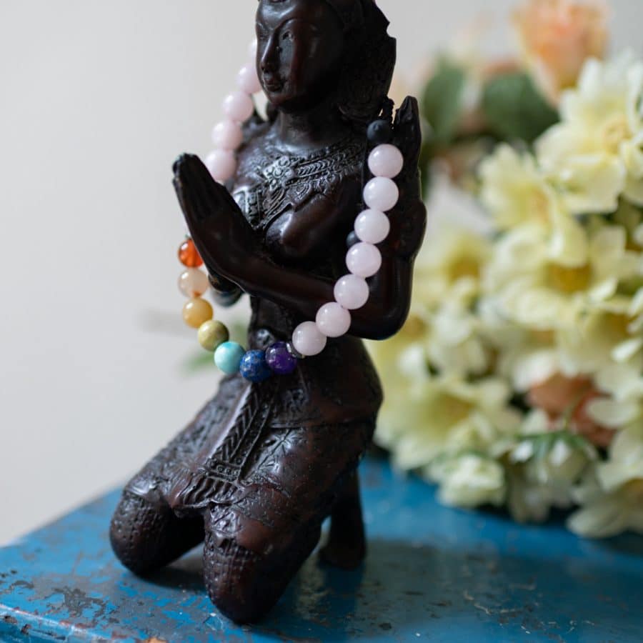braune figur mit chakra armband auf blauem schrank mit blumen