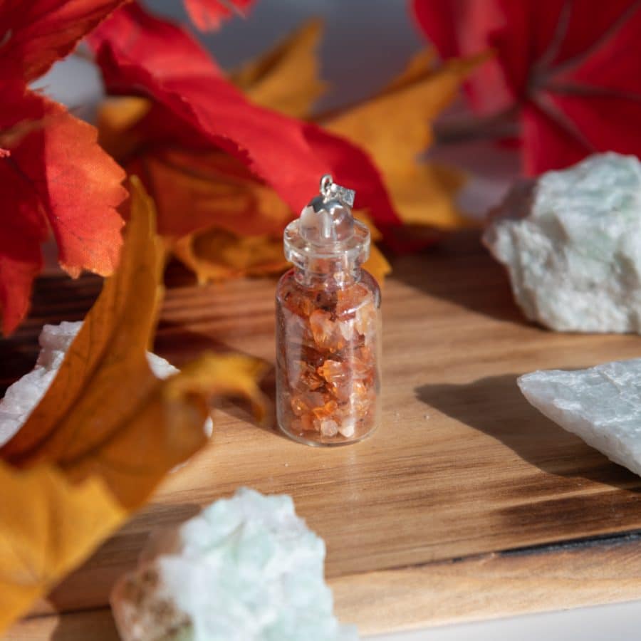 roter karneol in flasche mit steinen und blumen