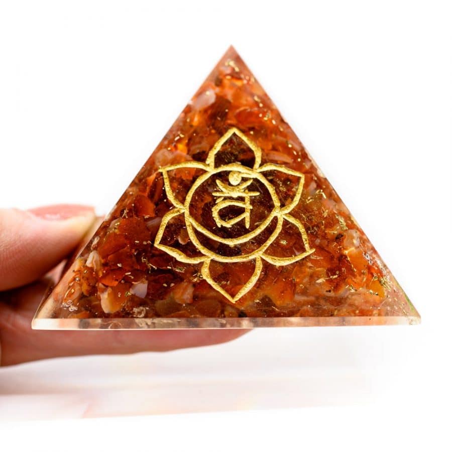 2. chakra pyramide rot symbol gold in hand vor weißem hintergrund