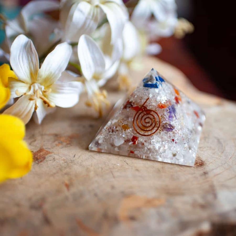 orgonit pyramide mit kupferspirale auf holz mit blumen